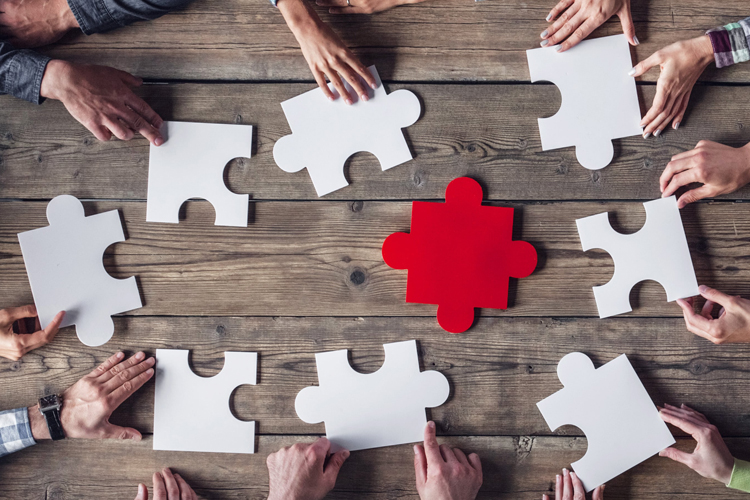 hands on table puzzling together puzzle with red piece
